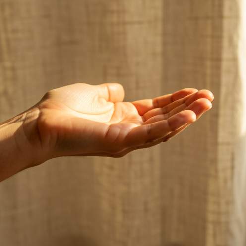 Main gauche ouverte, paume vers le haut, baignée d’une lumière dorée évoquant la spiritualité et l’intuition.